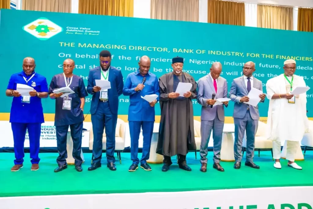Dr. Olasupo Olusi, Senator John Owan Enoh, and key stakeholders standing on stage reviewing official documentation during the Cocoa Value Addition Summit