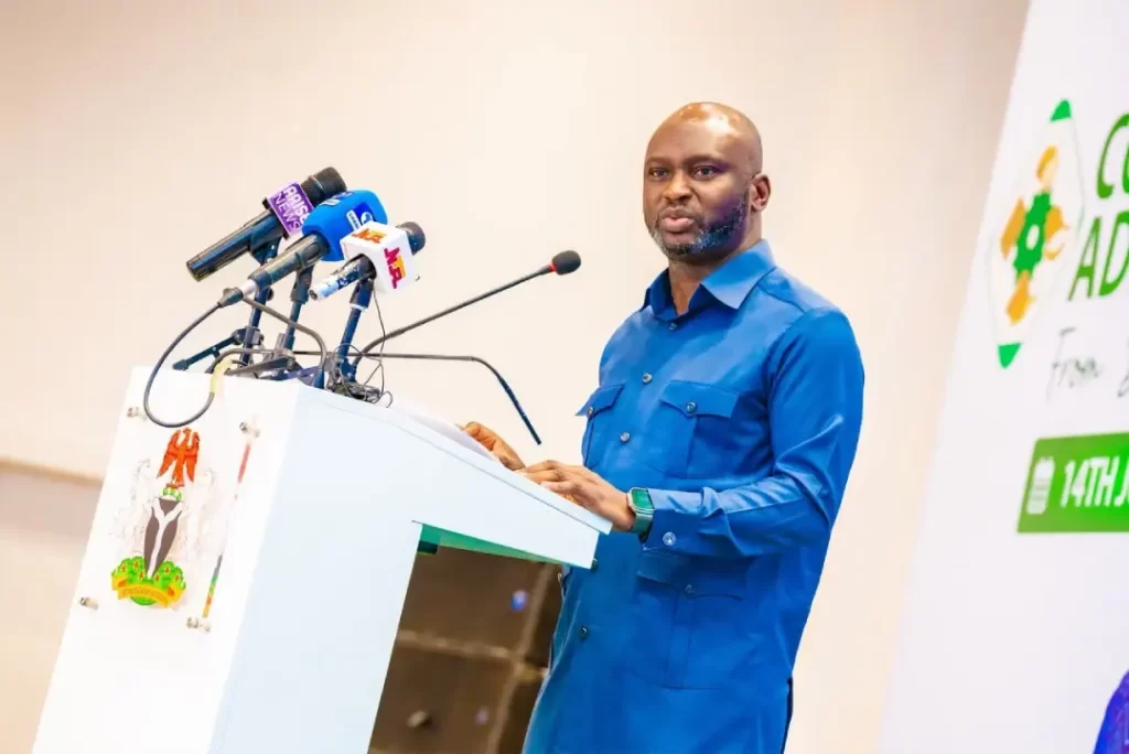 Close-up of Dr. Olasupo Olusi, Managing Director of the Bank of Industry, delivering a speech into multiple microphones at a white podium